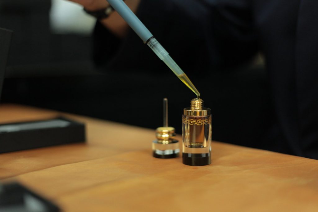 Oudh oil being transferred into a vial
