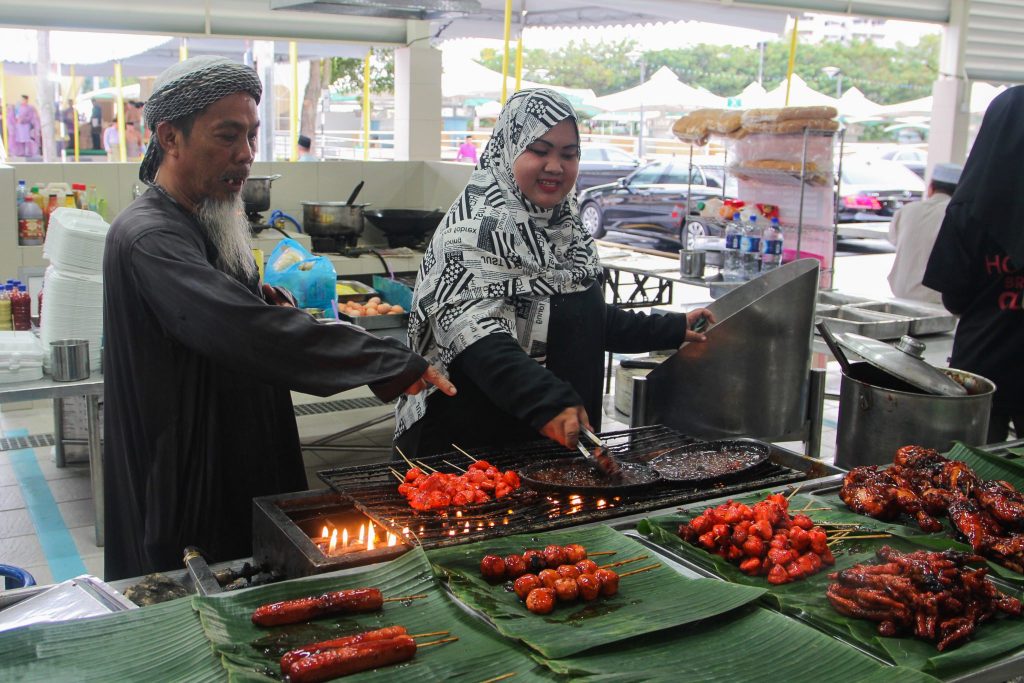 Hj Awg Damit Hj Awg Ismail (L) who has been selling in markets for three decades, operating at his new stall at the Gadong night market