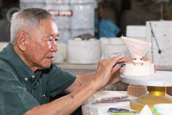 Hj Adnin using sandpaper to smoothen out a ceramic souvenir at Maha Seramik in Mumong. Photos by Faza Suraj.