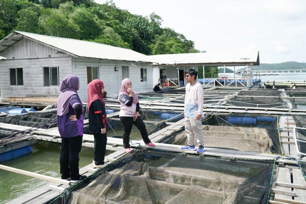 Fathi (L) in 2023 entertaining students visiting his fish farm in Pulau Kaingaran